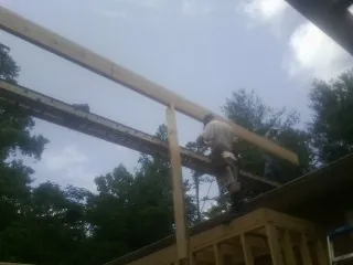 Carpenter setting a ridge beam over a new addition frame — Ice Dam Removal by Roofing Brothers in West River