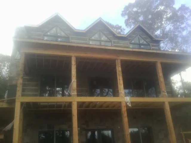 Dormers and porch framing on a large log home under construction — Roof Coating work by our crew in West River