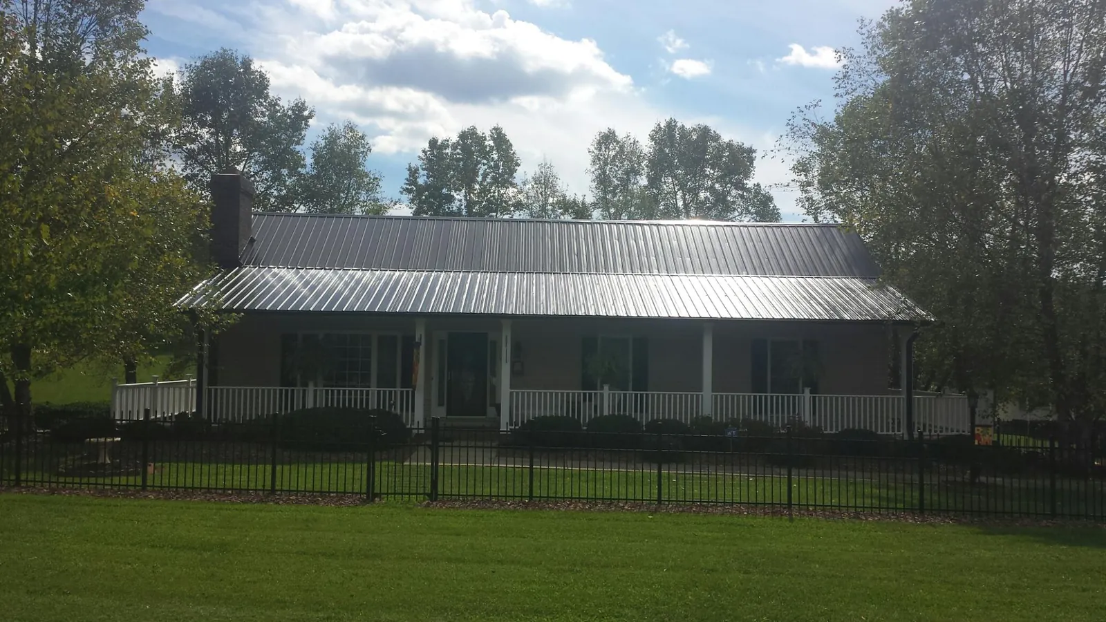 Gray metal roof on a brick ranch with a full width front porch — Gutter Guard Installation work by our crew in West River