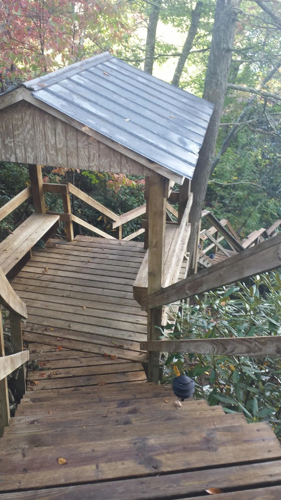 Metal roofed shelter over wooden steps on a wooded walkway — Skylight Repair & Installation work by our crew in West River