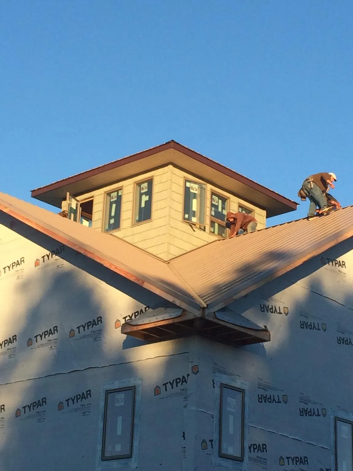 Roofers working around a rooftop cupola on a new metal roof at sunset — Roof Waterproofing in West River by Roofing Brothers